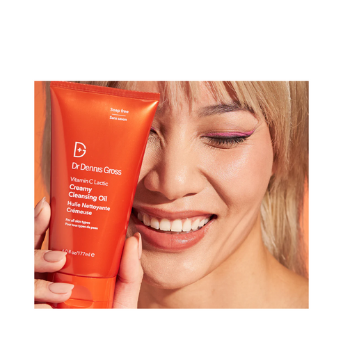 Happy woman with Dr Dennis Gross Cleansing Oil - Vitamin C, promoting its use as a nourishing face wash for glowing skin.